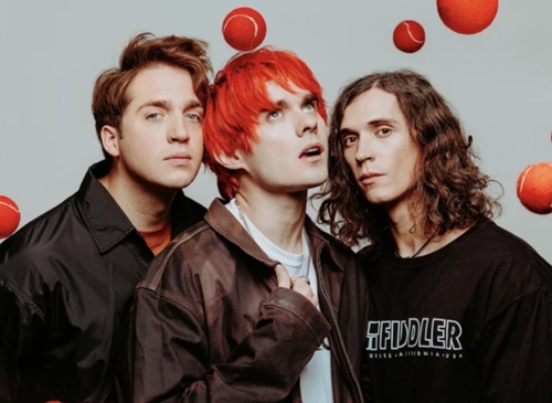 waterparks members posing together with red tennis balls falling in the background